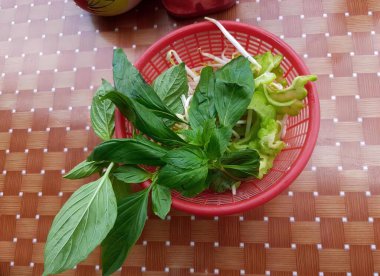 Kırmızı sepet, marul ve yeşil yapraklı bir bitki. Masadaki kırmızı sepetin içindeki nar yaprakları..