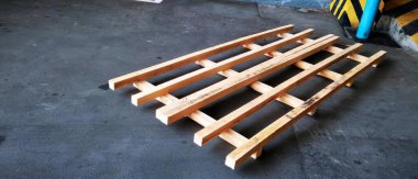 Yerde duran ahşap bir paletin fotoğrafı. Garajda beton zeminde ahşap paletler olan bir tabaka..