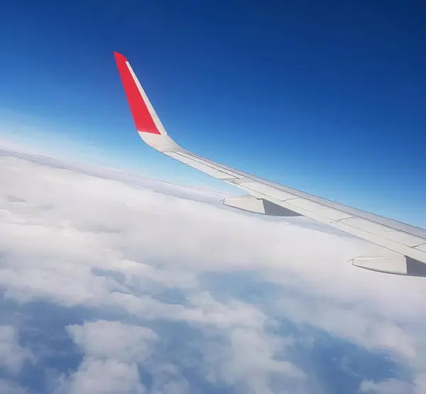 雲の上を飛んでいる飛行機の翼の写真 赤い尾で雲の上を飛んでいる飛行機の翼 — ストック写真