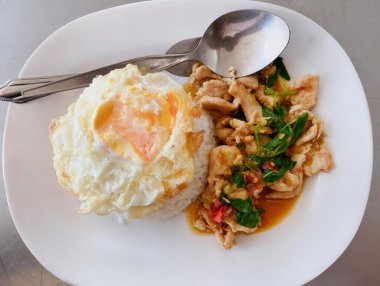 Çatal ve kaşıkla bir tabak yemeğin fotoğrafı, kızarmış yumurta, pirinç ve ıspanakla birlikte bir tabak yemek..