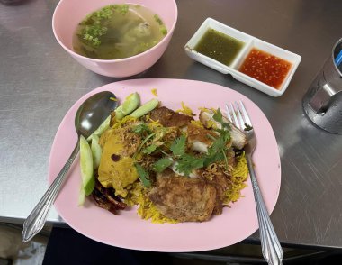 Üzerinde yemek olan pembe bir tabağın fotoğrafı. Pembe tabakta pilav ve sebzeli guacamole ve tavuk..