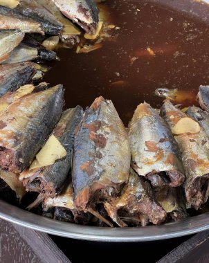 Masada balık ve sos dolu bir tavanın fotoğrafı, masada pişmiş balık ve sos dolu sıcak bir tencere..