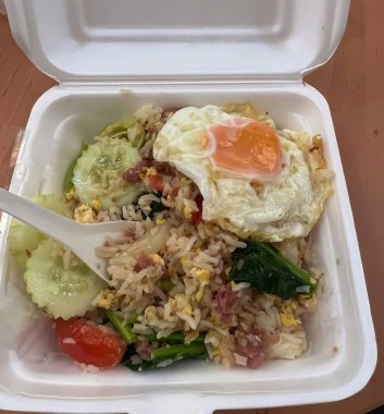 Kızarmış yumurta ve pilavla servis edilen bir konteynırın fotoğrafı, çatallı köpük bir konteynırda bir tabak yemek..