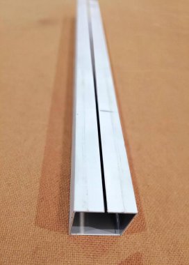 Bir masanın üzerindeki metal şeritin fotoğrafı, kahverengi arka planı olan bir masanın cetveli..