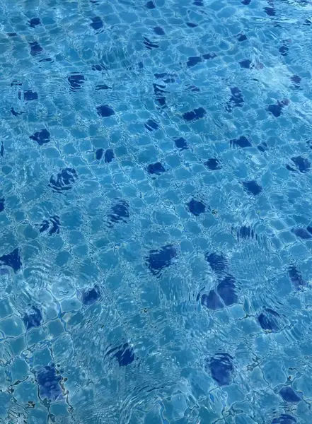 一个有蓝色水和白色飞盘的游泳池的照片 在一个有蓝色水和蓝色圆点的水池里舒缓 — 图库照片