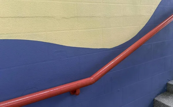 青い壁の赤い手すり写真 青と黄色の壁に繋がる バラードのステップ — ストック写真
