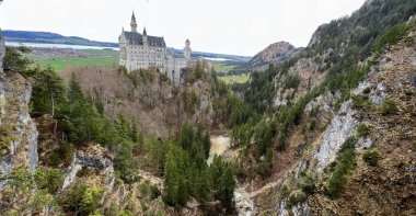 Dağın ortasındaki bir şatonun, nehre ve vadiye bakan bir uçurumun üzerindeki şatonun fotoğrafı..