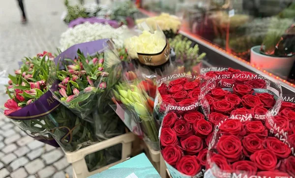外のテーブルの上のたくさんの花の写真 販売のための赤いバラや他の花の食料品店の表示 ストック画像