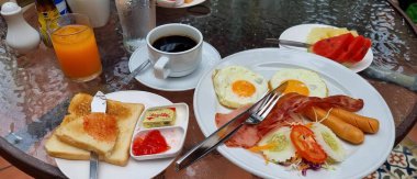 Bir tabak yemek ve bir fincan kahve ile bir masanın fotoğrafı. Masada bir tabak yemek ve bir fincan kahve var..