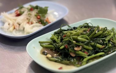 Bir tabak yemeğin yanında pilav, masada iki tabak yemek ve bir tabak yemek var..