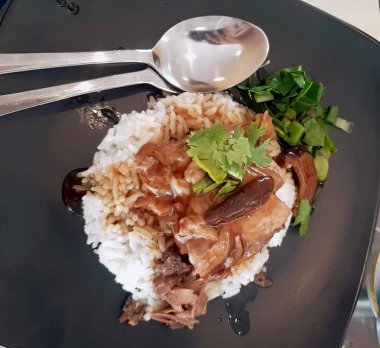 Pirinç, et ve sebzeli bir tabak yemeğin fotoğrafı. Üzerinde pirinç ve et olan bir tabak yemek var..