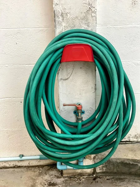 a green garden hose with a red lid.