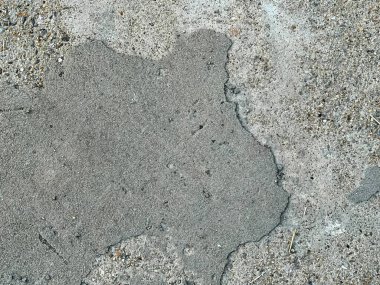 Küçük bir toprak parçasıyla beton bir yüzey fotoğrafı..