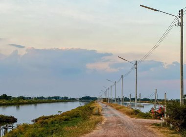 Arka planda nehir olan toprak bir yolun fotoğrafı..