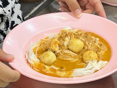 Elinde kaşık tutan bir insanla pembe bir yemek kasesinin fotoğrafı..