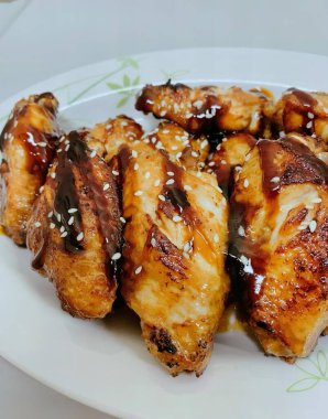 Bir tabak sosla kaplı tavuk kanadı fotoğrafı..