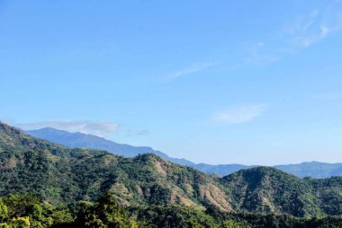 Birkaç ağaç ve birkaç tepenin olduğu bir dağ sırasının fotoğrafı..
