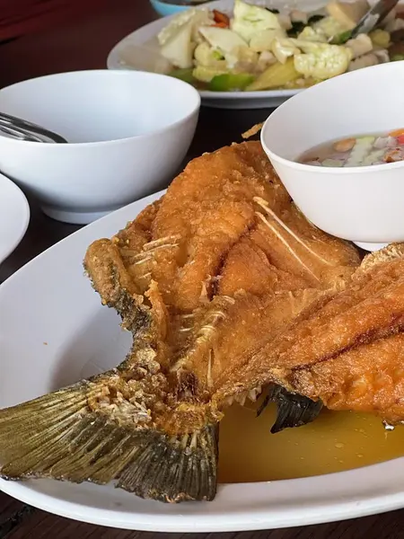 a photography of a plate of food with a fish and a bowl of soup.