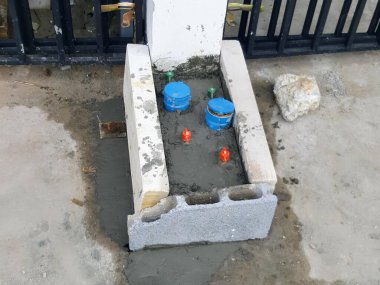 İki mavi varili ve mavi kovası olan beton bir yalağın fotoğrafı..