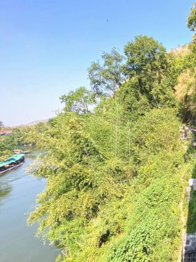Trenin bir nehir kenarındaki raylarda seyahat edişinin fotoğrafı..