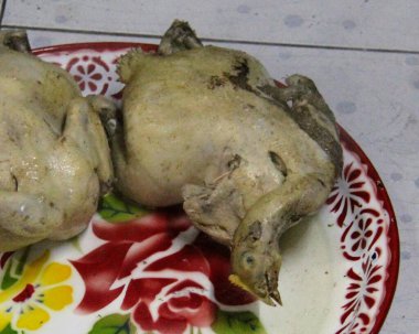 Tabakta çiçekli bir tabakla iki tavuğun fotoğrafı..