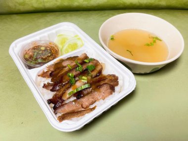 Eti ve bir kase çorbası olan plastik bir kabın fotoğrafı..