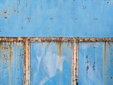 Paslı ve pencereli mavi bir duvarın fotoğrafı..