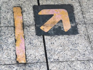 Üzerinde sarı ok olan bir tabelanın fotoğrafı..