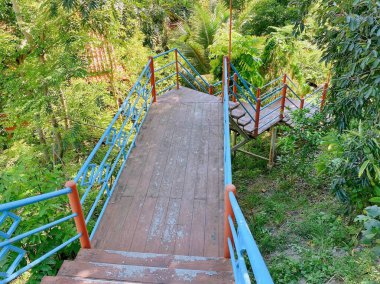 Mavi korkuluklu ve kırmızı korkuluklu ahşap bir geçidin fotoğrafı..