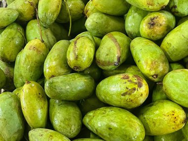 Masanın üzerinde duran bir yığın yeşil meyvenin fotoğrafı..