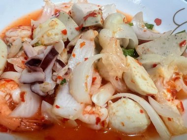 Karides, ahtapot ve diğer yiyeceklerin olduğu bir tabak yemeğin fotoğrafı..