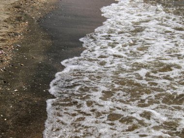 Sahile doğru gelen dalgalı bir sahilin fotoğrafı..
