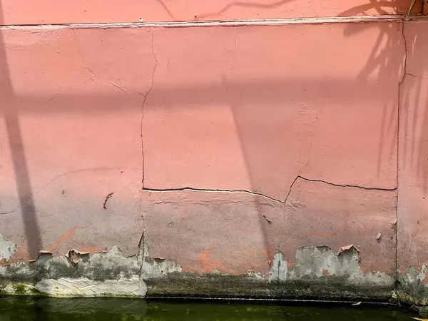 Pembe bir duvarın yanında duran kırmızı yangın musluğunun fotoğrafı..