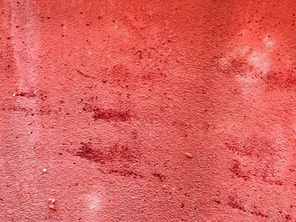 Üzerinde bir sürü leke olan kırmızı bir duvarın fotoğrafı..