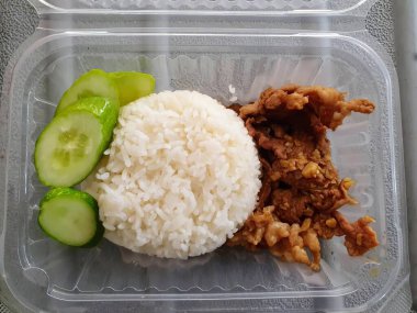 İçinde pirinç, salatalık ve et bulunan plastik bir kabın fotoğrafı..