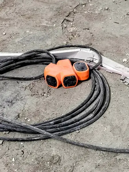 Bir çift turuncu ve siyah elektrik kablosu ve bir makas..