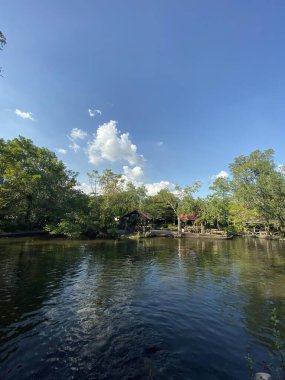 İçinde tekne olan bir gölün ve arka planda bir evin fotoğrafı..