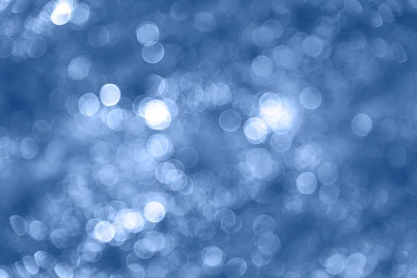 Abstract sharp bokeh of blurry highlights background. Soft focus bokeh light effects over a rippled, blue water background. Creative background for design projects, advertising, with copy space