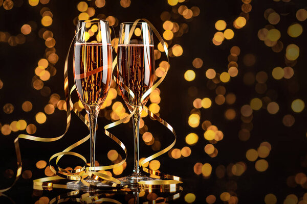 Два бокала с розовым шампанским и боке на черном фоне