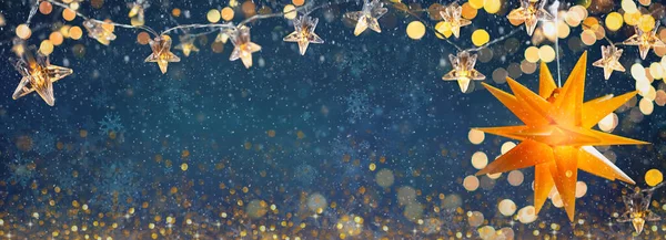Yellow shining star and Christmas garlands on a blue abstract background with bokeh and snowflakes