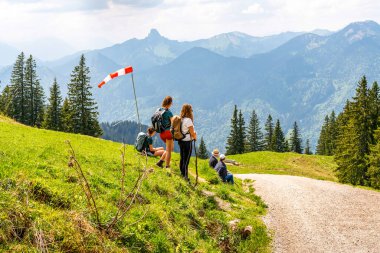 Bir grup turist yaz Alplerinde turistik bir yolda dinleniyor
