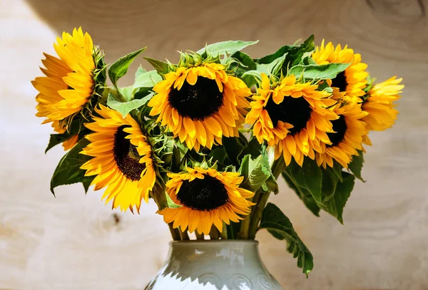 bouquet of sunflowers in a white vase on a wooden background