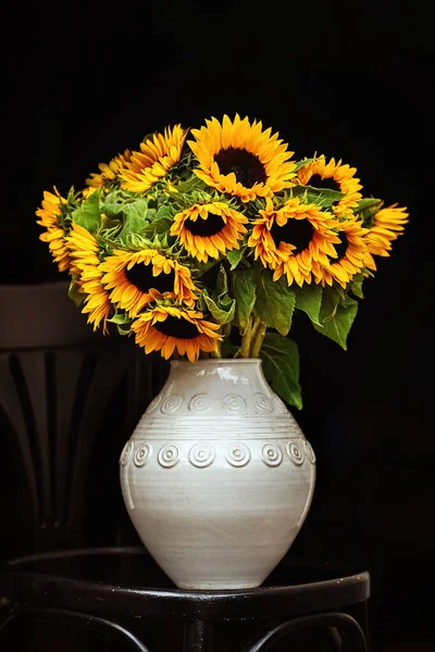 Bouquet of sunflowers in a white vase on a black background. isolate