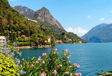 İtalya, Lugano Gölü. Göl manzarası, dağlar, gölün üzerinde duran evler..