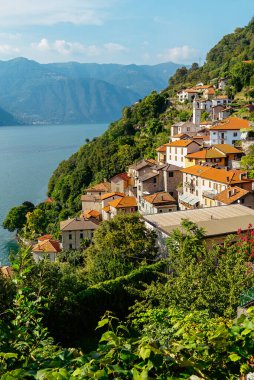 İtalya, Lugano Gölü. Göl manzarası, dağlar ve gölün üzerindeki eski evler..