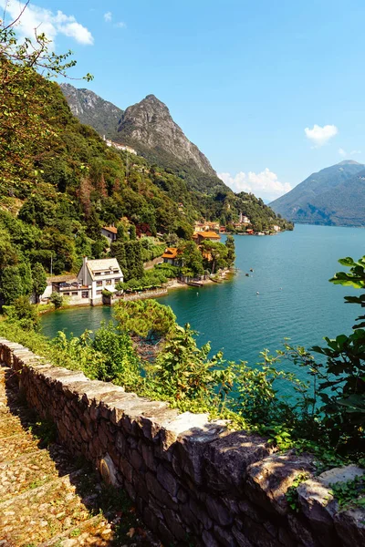 İtalya, Lugano Gölü. Göl manzarası, dağlar, gölün üzerinde duran evler..