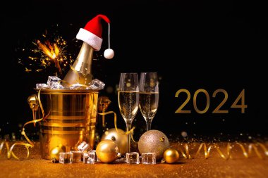 Altın kovada bir şişe şampanya, buzlu ve siyah ve altın arkaplanda iki bardak..