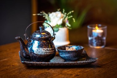 Seramik çaydanlık ve tahta bir masada kamış şekerli kase.