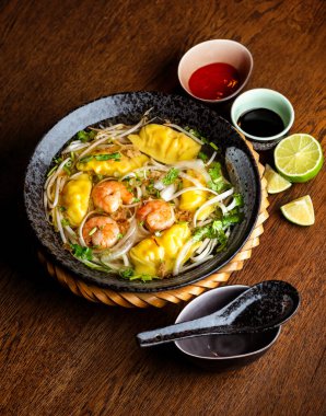 Siyah seramik tabakta karides ve hamur köftesi ile Asya çorbası.