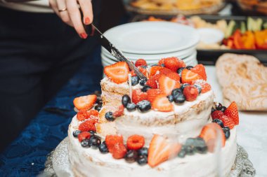 Beyaz kremalı, ahududu ve çilekle süslenmiş bir pasta.